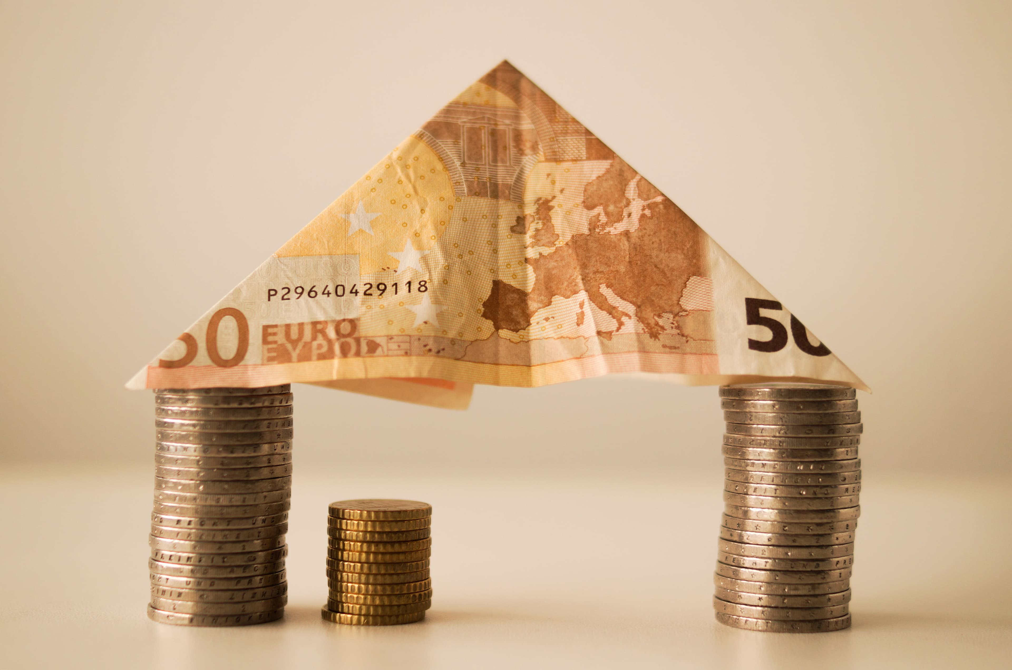 Biljet van 50 euro boven stapels euromunten als symbool voor koopkracht, sparen en economische ontwikkeling