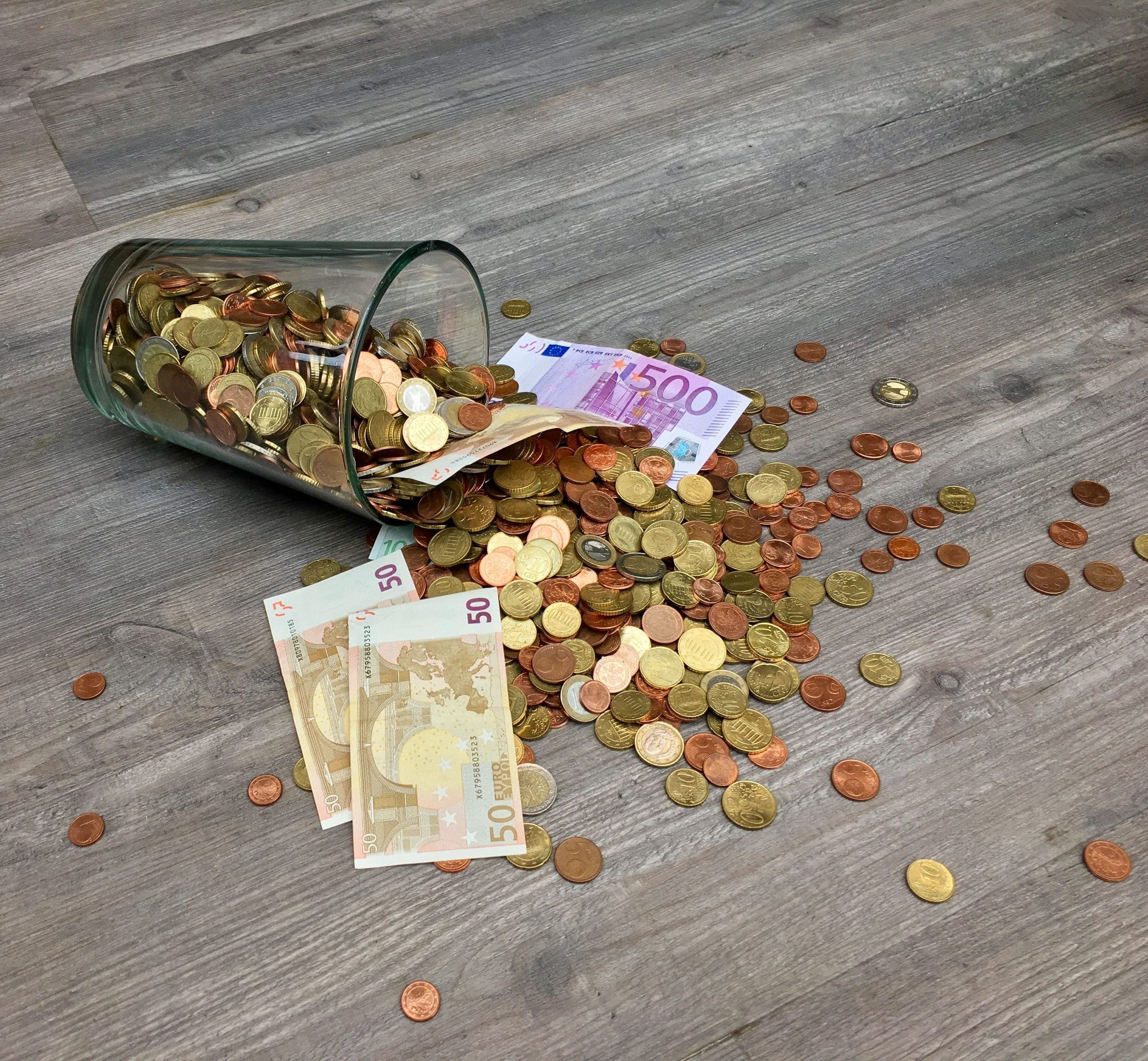 Glazen pot met eurobankbiljetten en euromunten als beeld van spaargeld bij een bank