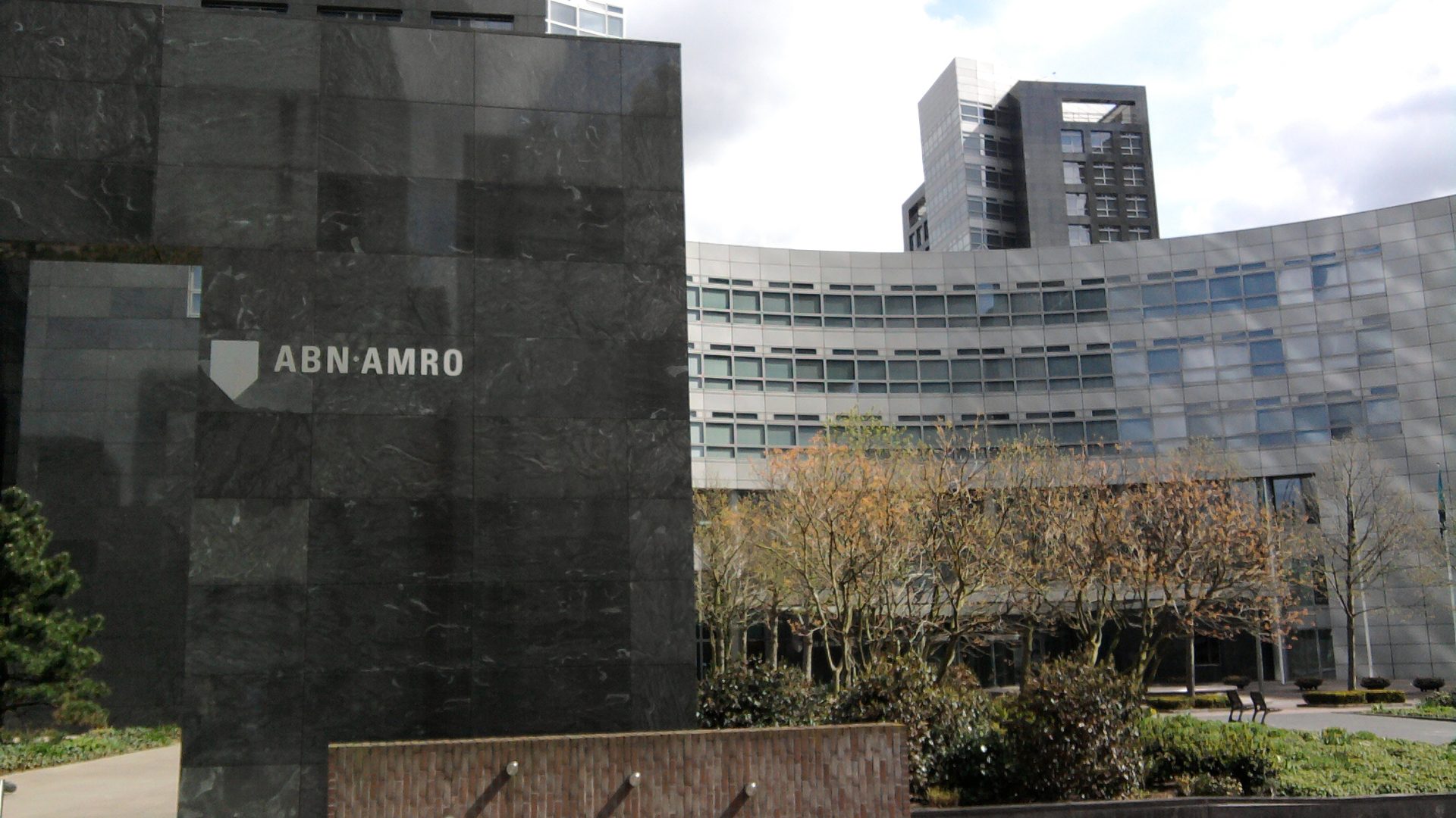 Het hoofdkantoor van ABN AMRO aan de Zuidas in Amsterdam, met het logo op een gevel van donkere natuursteen